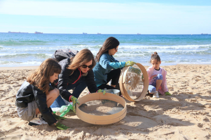 Cuatro voluntarias participen en la limpieza de la playa del Miracle de Tarragona.