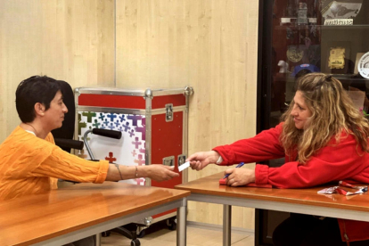 Una usuària rep una targeta moneder de Creu Roja per comprar productes de primera necessitat.