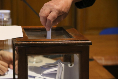 Imagen de detalle de uno de los votantes depositando su voto en la urna.