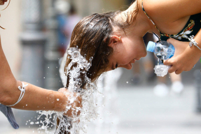 Una mujer se refresca en una fuente para combatir el calor.