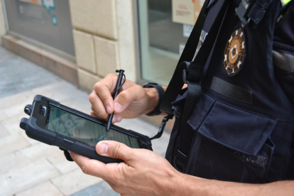 Un agente con una tableta electrónica realizando un trámite a pie de calle.