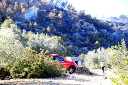 Un vehicle i un agent dels Bombers davant d'una zona cremada del Puig Moltó del Perelló encara fumejant.