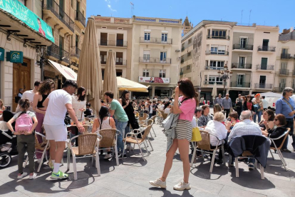 Imatge d'un migdia a la plaça del Mercadal, plena de gent a les terrasses o passejant.