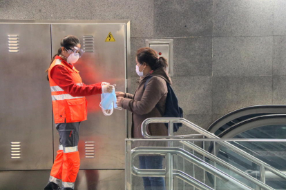 Pla obert d'una voluntària de la Creu Roja entregant una mascareta a l'estació de metro Diagonal de Barcelona.