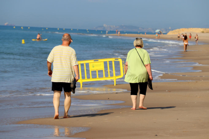 Dues persones passejant per la platja d'Altafulla.