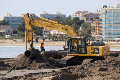 Dues persones treballant en les tasques de reposició de sorra a la platja de La Pineda.