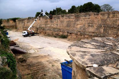 Operarios limpian con una grúa las murallas del foso del Sitjar donde se trabaja para construir un aparcamiento provisional del HTVC.