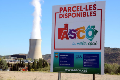 Primer plano de un cartel de promoción del polígono industrial de Ascó con la central nuclear al fondo.