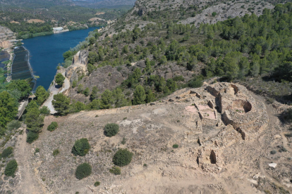 Imatge aèria del jaciment ibèric de l'Assut de Tivenys, amb l'estructura defensiva que corona el poblat, a la dreta, i el riu Ebre al fons.