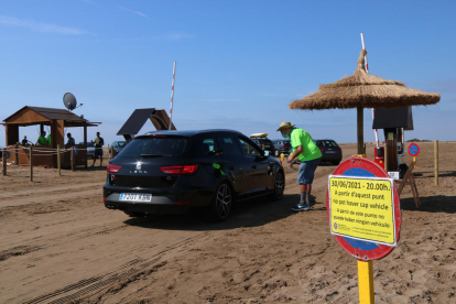 Pla general d'un agent cívic i d'un vehicle accedint a la platja del Trabucador en el primer dissabte de la nova regulació.