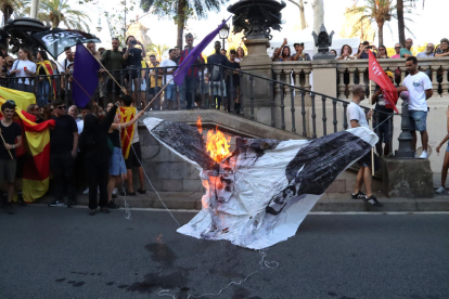 Uns encaputxats cremant una foto d'Aragonès i Collboni a la manifestació de l'esquerra independentista.