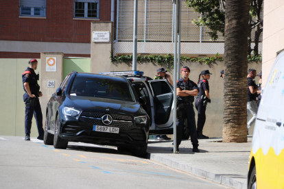 Agentes de los Mossos vigilando la puerta del edificio donde se encuentra atrincherado un hombre, en el barrio de Sarrià de Barcelona.