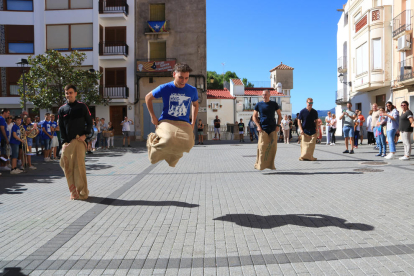 Cuatro jóvenes participen en la carrera de sacos de la primera edición de la 'Xalera' la primera jornada de juego y baile en la calle en la Sénia.