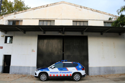 Un cotxe dels Mossos d'Esquadra custodia una de les portes d'accés de la nau del polígon Agroreus on s'ha dut a terme un dispositiu policial contra el tràfic de marihuana.