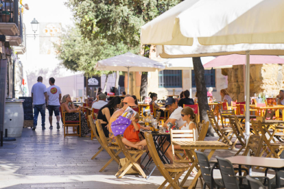 Imatge d'arxiu de diverses persones assegudes a les terrasses de la plaça del Fòrum.