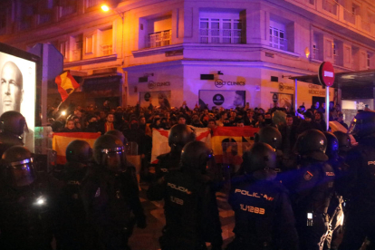 Manifestantes espanyolistas se encaran a policías nacionales antidisturbios detrás de banderas españolas.