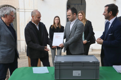 El director general de Memoria Democrática, Alfons Aragoneses, entrega la memoria de identificación de Narcís Mediavilla Cardó a sus nietos, frente a la caja que contiene los restos del soldado barcelonés.