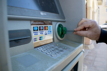 Una persona introdueix una targeta bancària en nou caixer automàtic.
