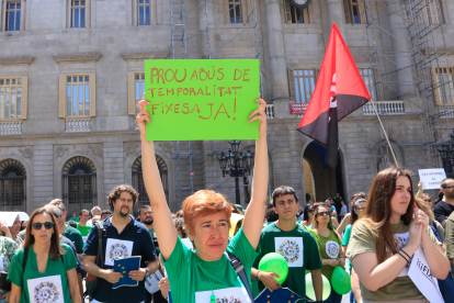 Un manifestant alça un cartell amb el missatge «Prou abús temporalitat, fixesa ja!», a la protesta d'interins a la plaça de Sant Jaume