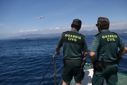 Dos agents de la Guàrdia Civil observen com l'helicòpter de Salvament Marítim maniobra en un simulacre a la costa de Cambrils.