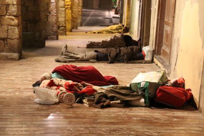 Quatre persones dormint en un dels carrers de la Part Alta de Tarragona.