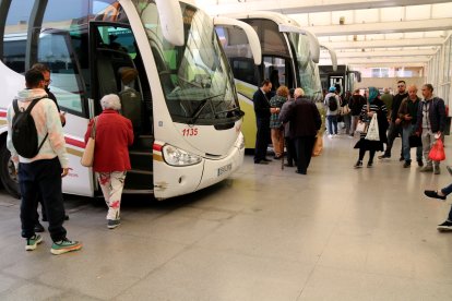 Desenes de passatgers pujants als autobusos a l'estacio de Tortosa.