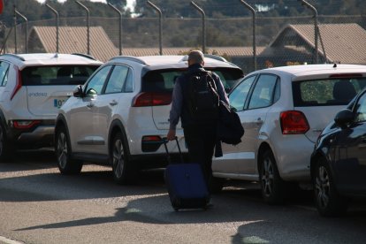 Un home amb una maleta caminant pels vorals de l'entrada de l'estació del Camp de Tarragona després d'aparcar-hi el seu vehicle.