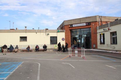 Usuaris esperen l'autobús llençadora a l'exterior de l'estació de tren de Sant Vicenç de Calders.