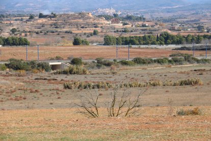 Terrenys del futur Logis Montblanc, amb un poble al fons i la línia de l'AVE en primer terme.