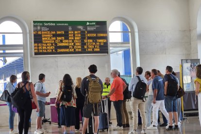Usuaris observant un panell informatiu a l'estació de Lleida.