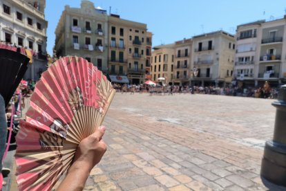 Una persona abanicant-se ahir a la plaça del Mercadal de Reus.
