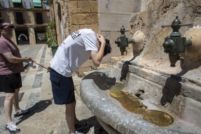 Un jove es refresca en una de les fonts de les escales de la catedral de Tarragona buscant alleujar les altes temperatures.