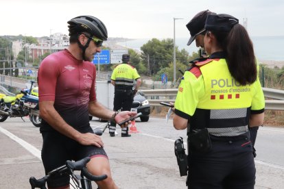 Un ciclista mostra la seva documentació als Mossos d'Esquadra en un control de trànsit.