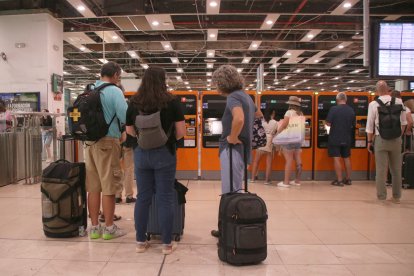 Persones esperant per utilitzar una màquina de venda de bitllets a l'estació de Sants