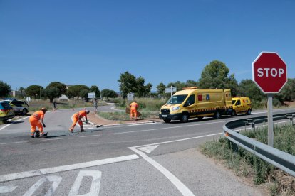 Treballadors de carreteres de l'estat treballen després d'un accident mortal, prop d'un senyal d'stop per accedir a una de les entrades de Montbrió del Camp
