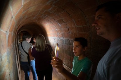 Visitants llegint missatges escrits a les parets del refugi antiaeri de la Patacada.