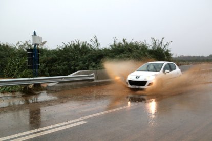 Un cotxe creua un bassal d'aigua i fang a la C-12