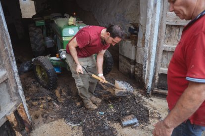 Un veí traient fang d'un local a Godall.