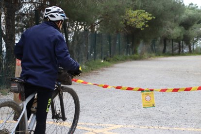 Un ciclista llegint el cartell que indica la prohibició d'accedir a Collserola a la carretera de les Aigües de Barcelona.