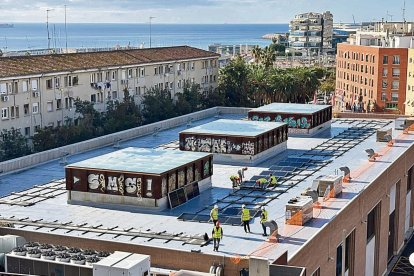 Imatge dels operaris instal·lant les plaques solars a la coberta del Palau Firal.