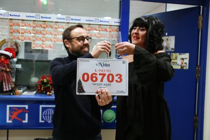 Dos trabajadores de la administración Doña Pilar de Salou brindando con cava y mostrando el cartel del primer premio del Sorteo del Niño.
