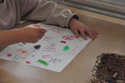 Imatge d'un nen fent un dibuix en una escola.