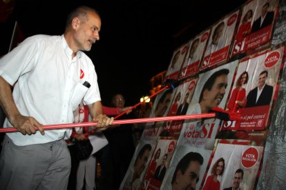 El cap de llista del PSC per Tarragona, Joan Ruiz, enganxant un cartell amb una escombra a la Rambla Nova de Tarragona.