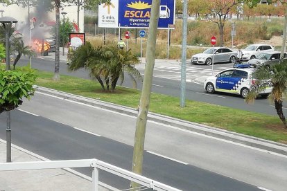 Imagen del contenedor quemado y un vehículo de la Guardia Urbana de Reus llegando al lugar.