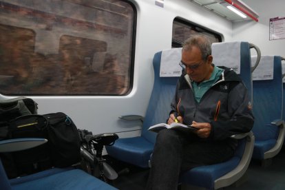 En Josep Maria, un professor universitari, agafa apunts d'un llibre durant el seu trajecte a Barcelona amb l'R15.
