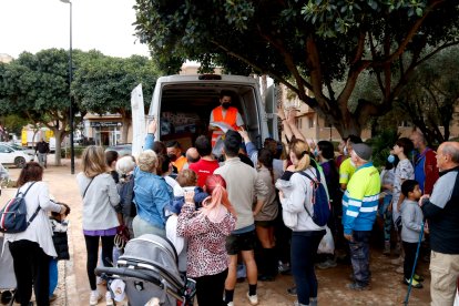 Diverses persones agafen botes d'aigua que es reparteixen des d'una furgoneta a Aldaia