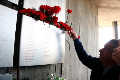 Un home col·loca un clavell vermell a la placa on es recorden els combatents de la batalla de l'Ebre