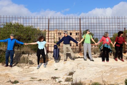 Diverses persones formant una cadena humana en contra del camí de ronda entre l'Arrabassada i la Savinosa amb l'edifici del preventori al fons