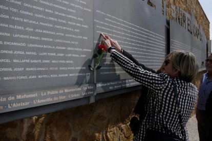 La expresidenta del Parlamento, Carme Forcadell, señala el plafón|panel donde constan las víctimas de la represión franquista enterradas a una de las fosas|fosos comunes de Tarragona