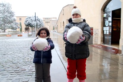 Dos niños muestran las bolas de nieve que han hecho en el monasterio de Poblet.